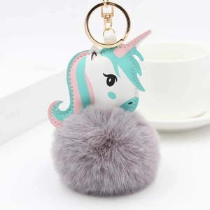 Détail d'un porte-clés licorne en peluche avec une boule en fausse fourrure grise et fermoir