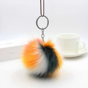 Detail of soft tri-color faux fur pom pom keychain with silver ring and lanyard