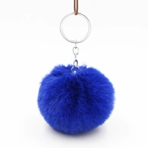 Close-up of fluffy royal blue faux fur pompom keychain with polished silver metal ring