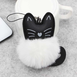 Détail d'un porte-clés chat en fourrure blanche avec visage en cuir noir et détails brodés