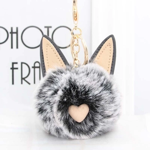 Gros plan du porte-clés chat en peluche gris et blanc avec fermoir mousqueton doré chic