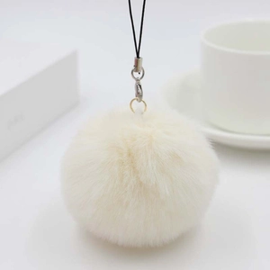 Close-up of fluffy off-white faux fur ball keychain with metal clasp and black lanyard