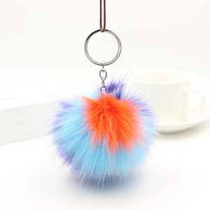 Detailed macro view of a fluffy tricolor faux fur pom pom keychain with a woven lanyard