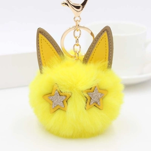 Détail d'un porte-clés chat en peluche jaune avec yeux étoiles dorés et fermoir en métal