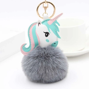 Détail d'un pompon en fausse fourrure grise et porte-clés licorne avec crochet doré
