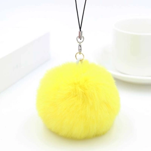 Close-up of fluffy lemon yellow faux rabbit fur pompom charm with black mobile phone lanyard