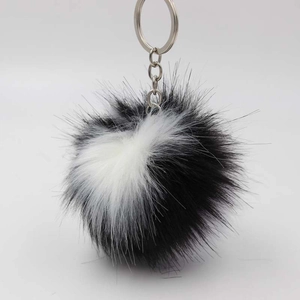 Detail view of a fluffy black and white faux fur pompom keychain with silver metal ring