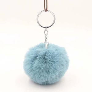 Detail shot of light blue faux fur pompom keychain with silver metal ring and chain