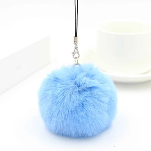 Detail of light blue faux fur pompom keychain with silver lobster clasp and phone strap