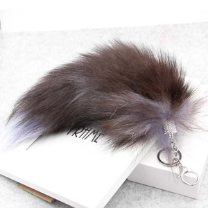 Close-up of a large fluffy fox tail keychain with metal ring and lobster clasp detail