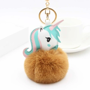 Vue détaillée porte-clés licorne en cuir blanc avec pompon en fausse fourrure marron