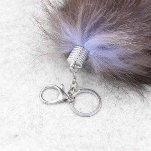 Close-up of fluffy fox tail keychain showing dark brown and lilac fur with silver clasp