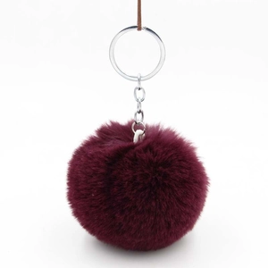 Detailed close-up of a burgundy faux rabbit fur pompom with silver metal key ring and chain