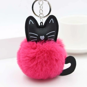 Close-up of pink fluffy pom-pom keychain with black faux leather cat face and metal ring