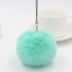 Close-up of fluffy mint green faux fur pom pom keychain with silver metal ring