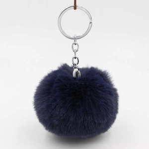 Close-up of fluffy navy blue faux rabbit fur pompom keychain with silver metal ring