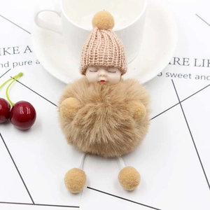 Cute sleeping baby doll keychain with plush khaki fur ball and pink knit hat accessory