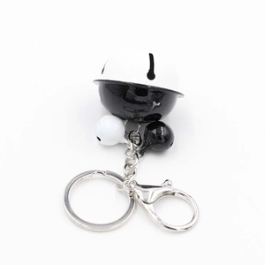 Close-up of star-hollowed black and white bell charm with metal lobster clasp and ring