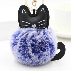 Detailed macro view of a fluffy two-tone faux fur cat keychain with a black PU leather cat face