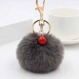 Flauschiger grauer Kunstfell-Bommel-Schlüsselanhänger mit roter Glocke und Gold-Metall