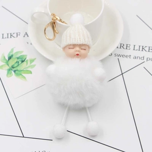 Close-up of sleeping baby doll keychain with white pompom and golden metal clasp