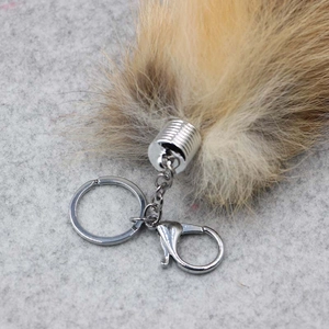 Macro view of silver lobster clasp and hardware attached to fluffy fox tail keychain