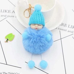 Detail of light blue plush sleeping baby keychain with knit hat and golden clasp