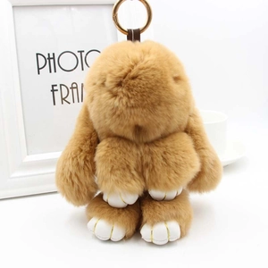 Détail de porte-clés lapin en peluche marron avec griffes dorées et anneau en métal