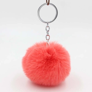 Detail view of a fluffy coral pink pompom keychain with a polished silver metal ring