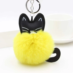 Detail of cute cat plush keychain with a bright lemon yellow faux fur pom pom and silver ring