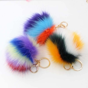 Détail de porte-clés pompons colorés en fausse fourrure avec fermoir doré sur fond blanc