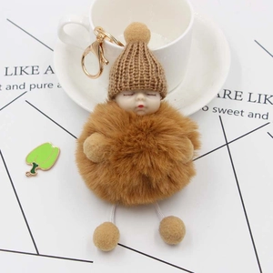 Detail of cute brown sleeping baby plush keychain with gold clasp on white cup