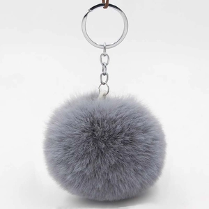 Close-up of a soft grey faux fur pompom keychain with a silver metal ring and chain link