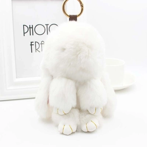 Détail d'un porte-clés lapin en peluche blanche avec fermoir doré et broderie
