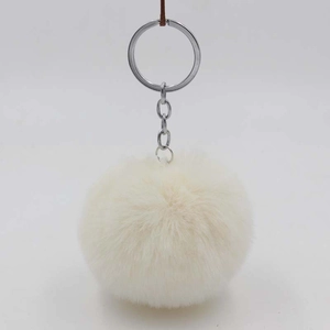 Detail view of the soft ivory faux fur pompom keychain with silver metal ring and chain