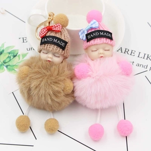 Dettaglio dei simpatici portachiavi a pompon con testa di bimbo nei colori rosa e kaki