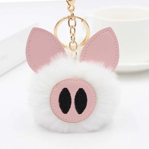 Détail d'oreilles et museau de cochon en simili cuir rose sur un porte-clés pompon blanc