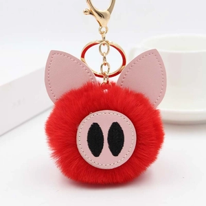Détail d'un porte-clés cochon en peluche rouge avec fausse fourrure et fermoir doré