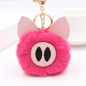 Gros plan d'un porte-clés pompon cochon rose en peluche avec un fermoir doré brillant