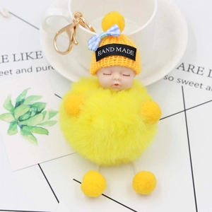 Dettaglio ravvicinato del portachiavi bambola che dorme in peluche giallo con metallo dorato