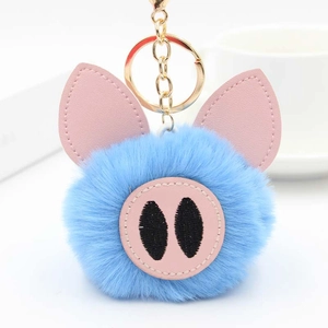 Détail d'un porte-clés cochon en peluche bleue avec oreilles en cuir et fermoir doré