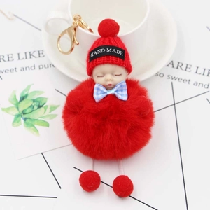 Détail du porte-clés bébé endormi avec pompon rouge et fermoir en métal doré