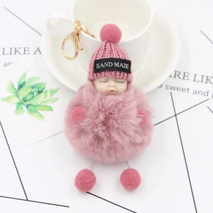 Pink sleeping baby plush doll keychain with pom pom and handmade knit hat on bag