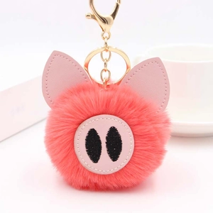 Détail d'un porte-clés cochon en peluche rose avec fausse fourrure et fermoir doré
