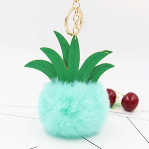 Detail of plush pineapple keychain with green PU leaves and mint pom-pom on white surface