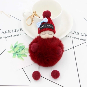 Dettaglio del portachiavi a bambola neonato rosso in peluche con fiocco e gancio