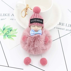 Porte-clés poupée bébé endormie rose avec pompon en peluche, bonnet en tricot et nœud bleu