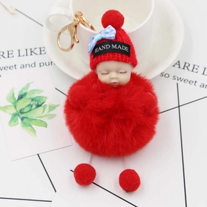 Dettaglio portachiavi bambola che dorme con pompon rosso e cappello lavorato a maglia