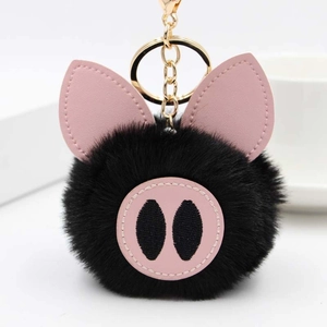 Détail d'un porte-clés cochon en peluche noire avec oreilles en cuir rose et clip doré