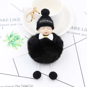 Détail d'un porte-clés poupée bébé endormi en peluche avec pompon noir et un joli nœud